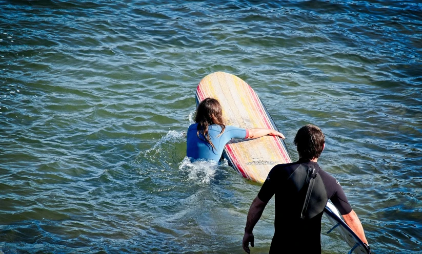 a man and woman on surfboards in the ocean