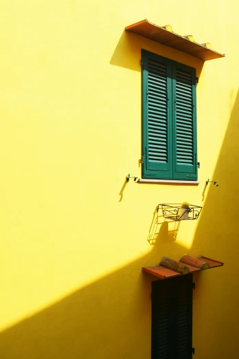 a yellow wall with two green shutters and a wooden table