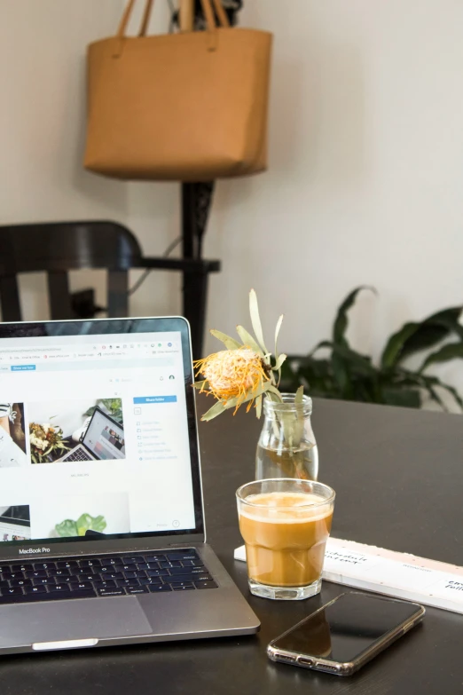 a glass with a beverage on it near a laptop