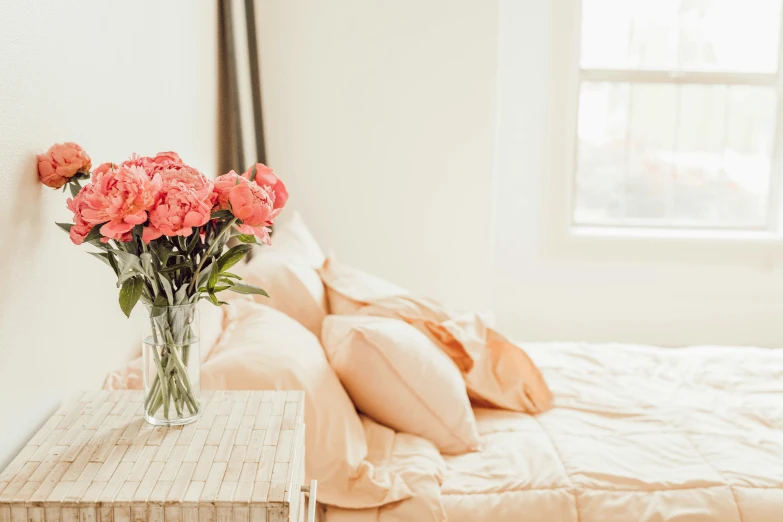 bouquet of pink roses in a glass vase sitting on a small end table