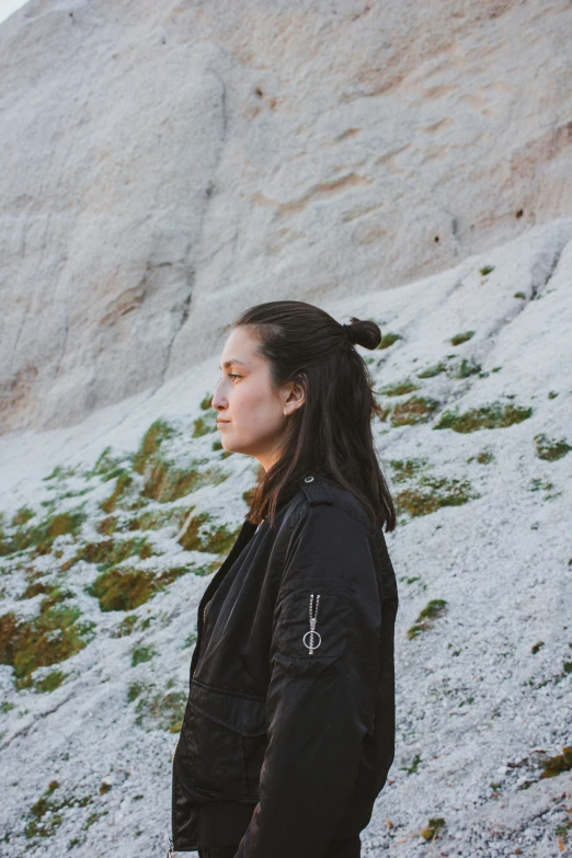 a woman in black jacket near large rock