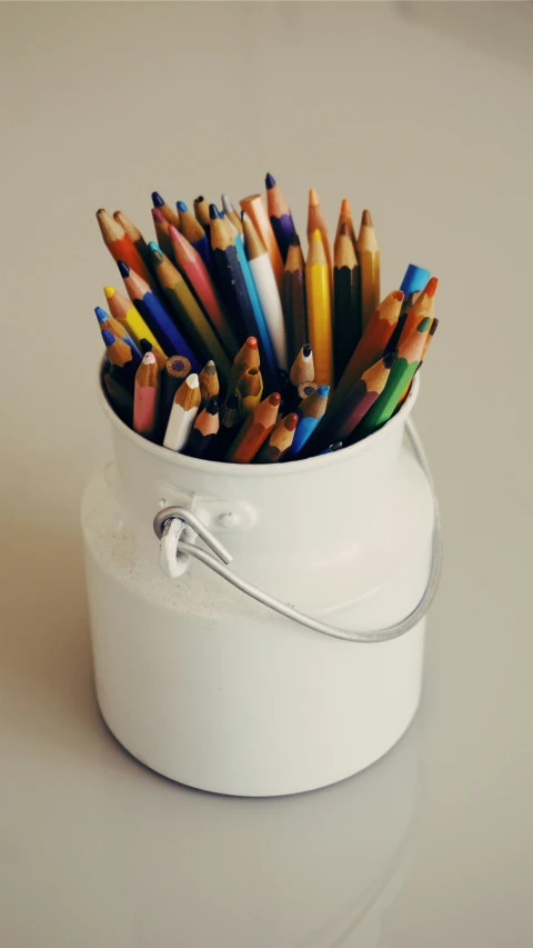 a container filled with lots of colored pencils on a table