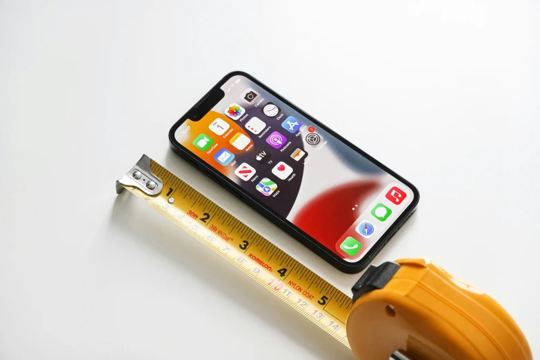 a cell phone and measuring tape are arranged on top of a table