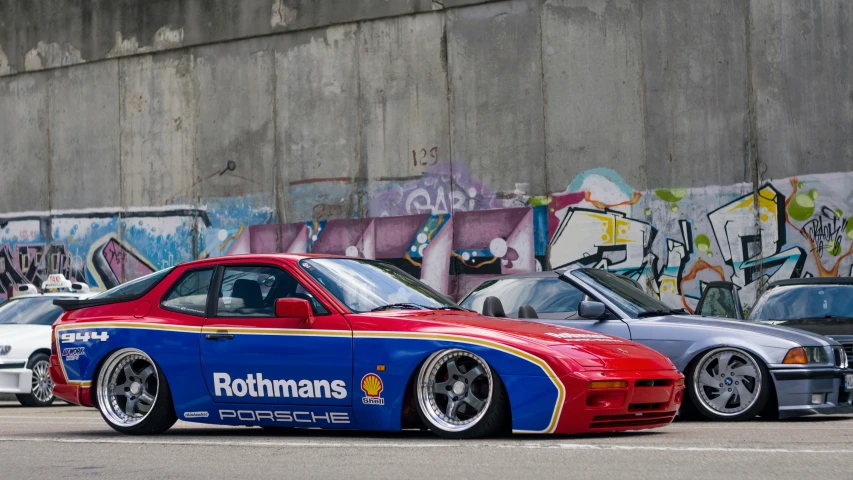 a pair of cars parked in front of a graffiti wall