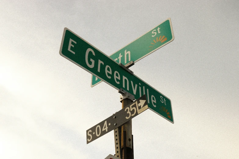 two green street signs mounted to the top of a metal pole