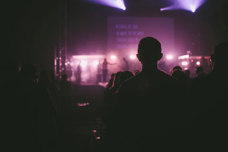 a dark image of the back of a man in a dimly lit auditorium