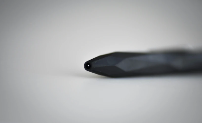 a pen resting upon a white surface, with a slight reflection