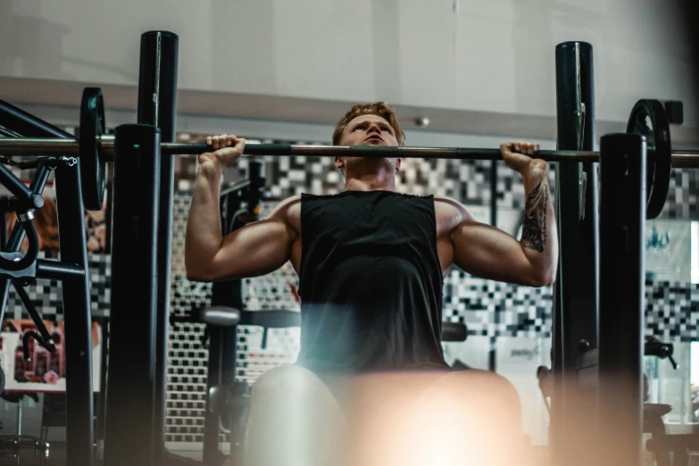 a man lifting two black barbells while working out