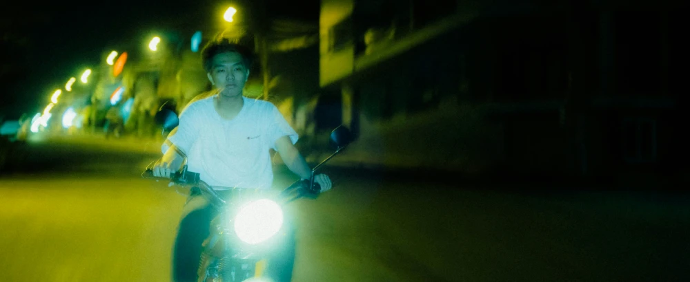 a man is riding down the street on his motorcycle at night