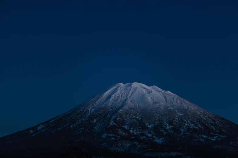 a snow capped mountain is illuminated by the moon