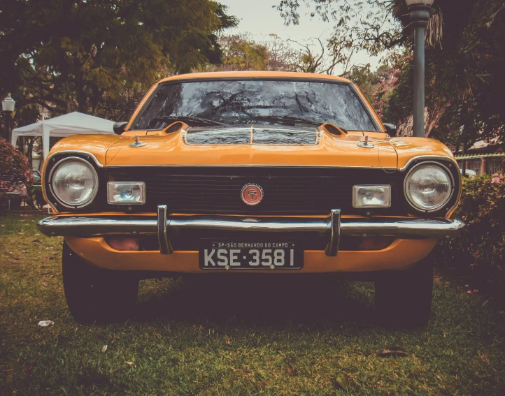 a vintage, yellow ford car is parked in the grass