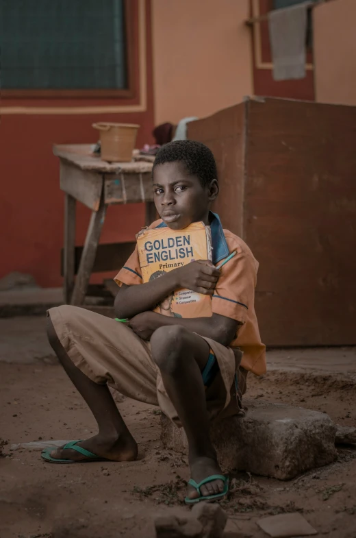 a boy is sitting on a rock holding a book