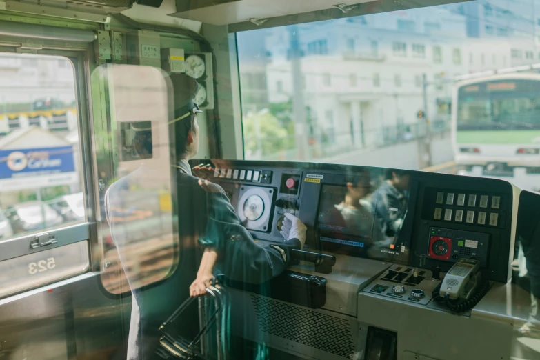 woman with short hair standing next to a bus and looking at a train monitor