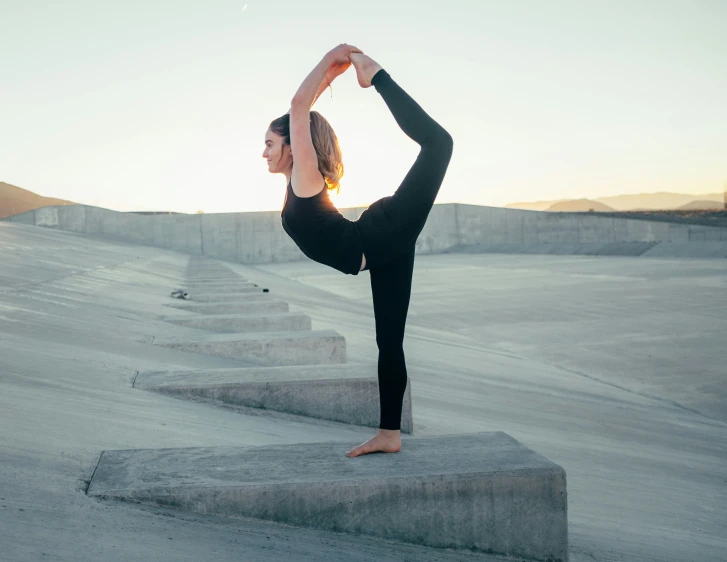 a woman is doing yoga poses in a sandy field