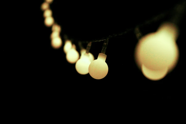 a string of white light bulbs hanging from a dark sky