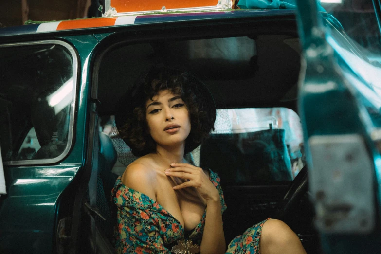 woman in floral dress seated inside car and looking at camera