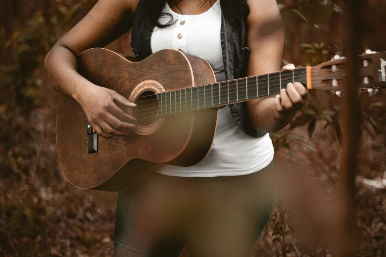 a woman standing in the woods with a guitar