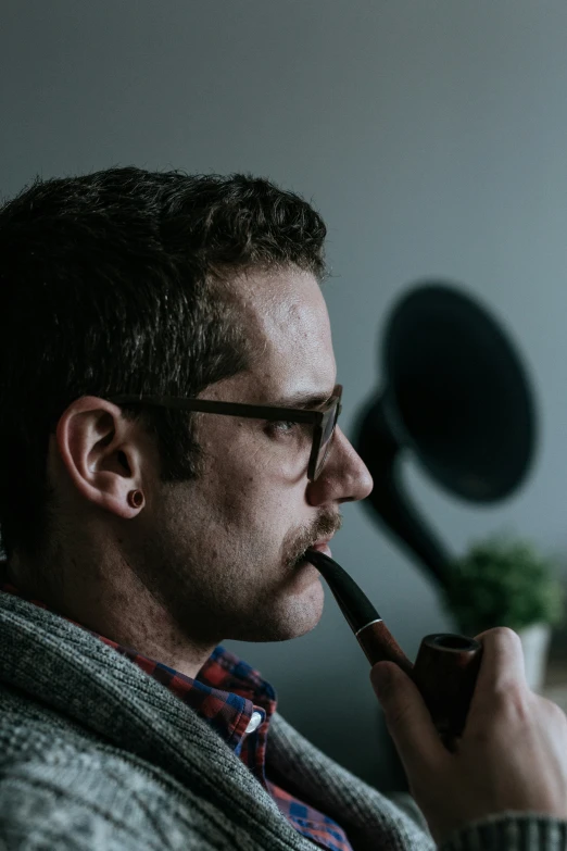 a man with glasses on smoking a pipe