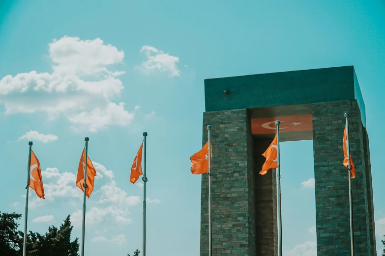 a number of orange flags flying near a building