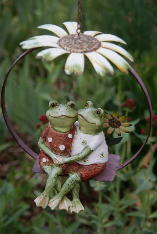 two frog ornaments hang in a garden