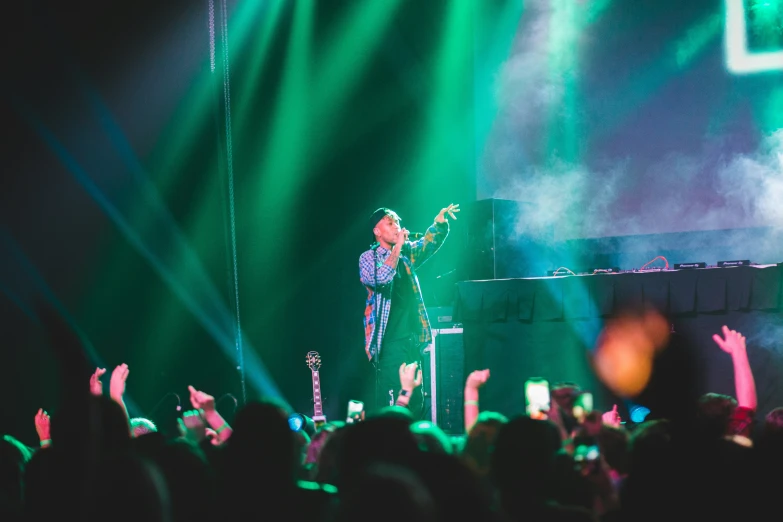 people in front of green lights and stage lighting at a concert