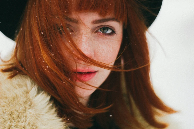 a woman with red hair and hat, and blue eyes