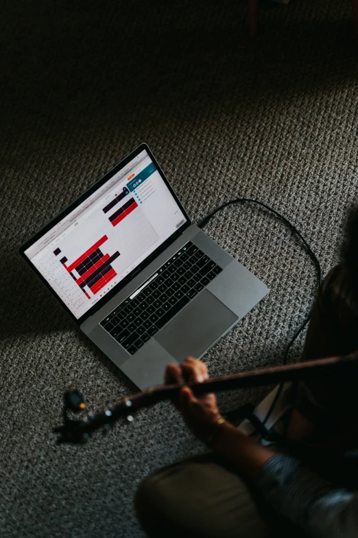 a laptop computer sits on a carpet with an instrument