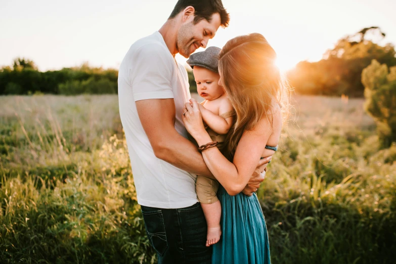 a couple and their son playing together at sunset