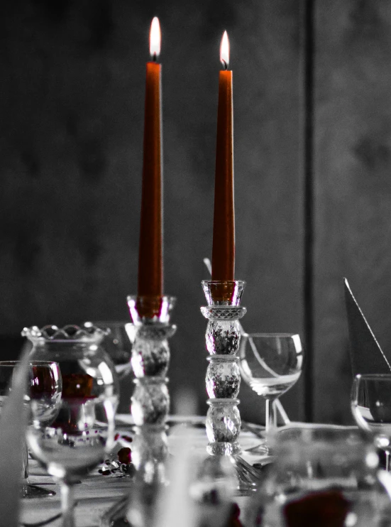 two candles sit on a table where all glasses are on the table