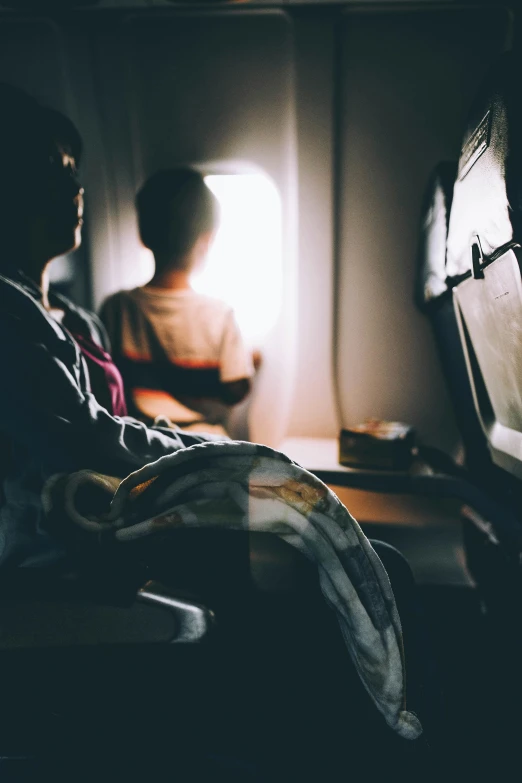 the young people sit on the airplane and look at the small window