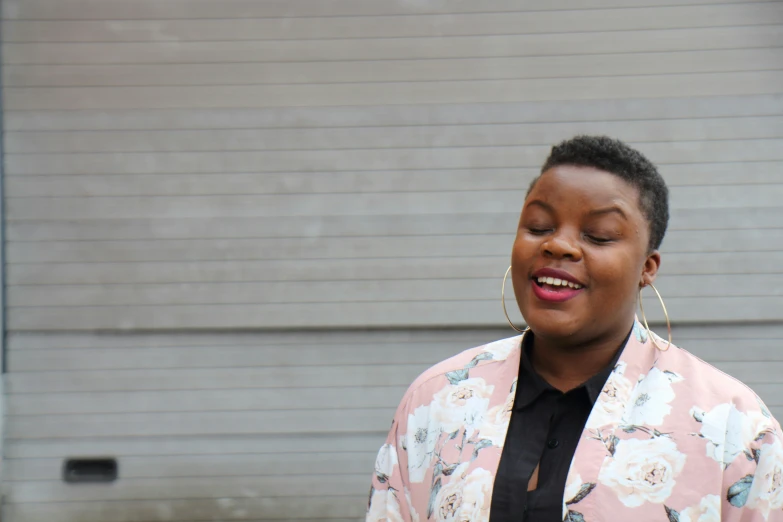 a woman wearing pink and black stands by a garage door