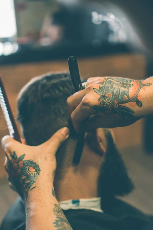 a man is having a tattoo done by his friend