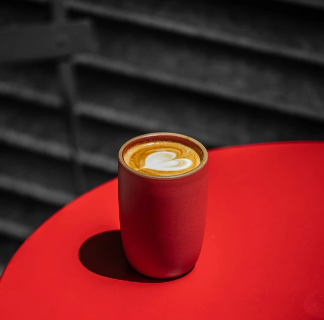 a cup of coffee is on top of a red table