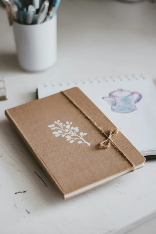 an old notebook with a bow tied to it sitting on a white desk