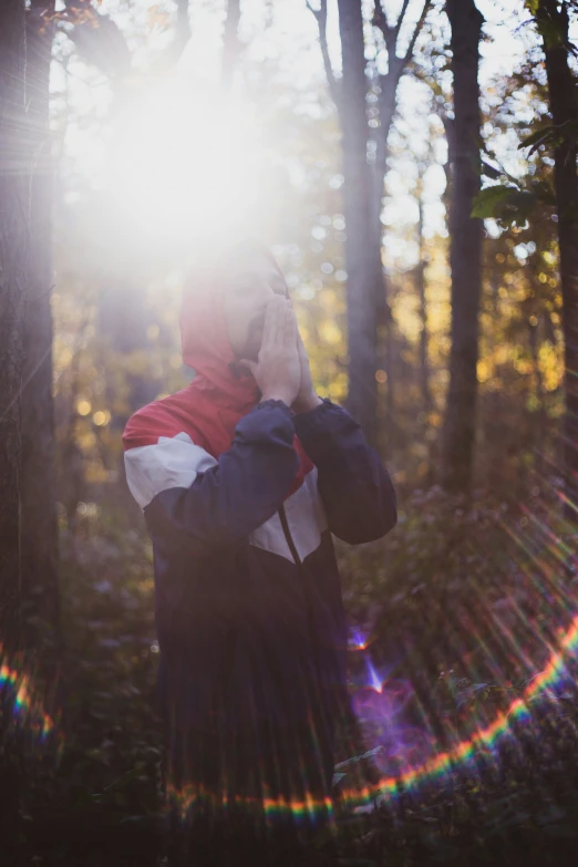 a woman standing in the woods talking on a cellphone