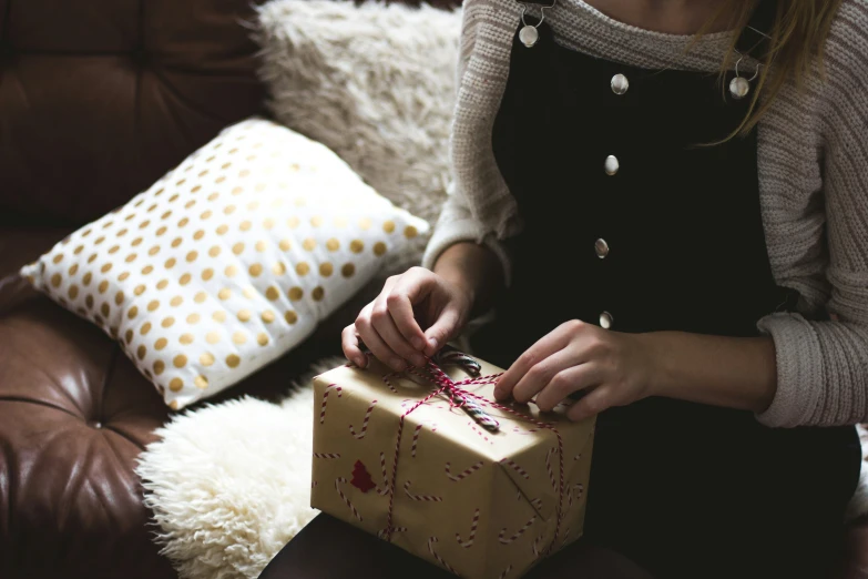 the woman sits on a couch holding a christmas present