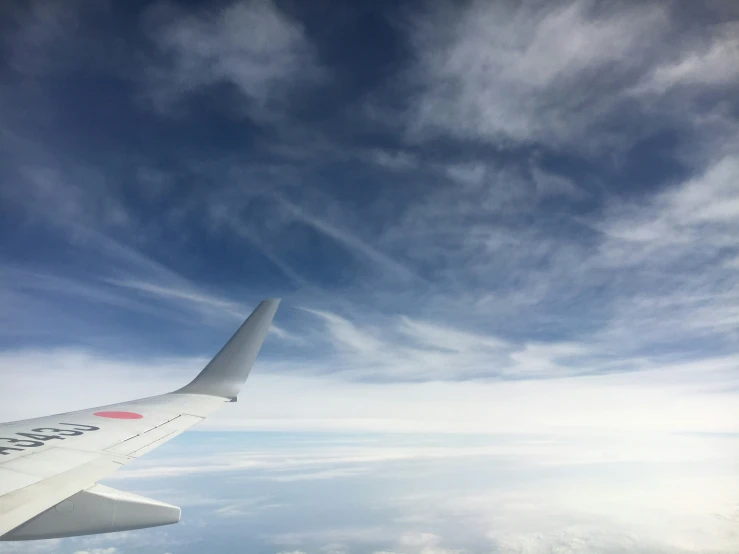 a plane wing in the sky above clouds