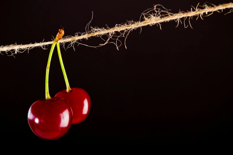 two cherries are hanging on the vine