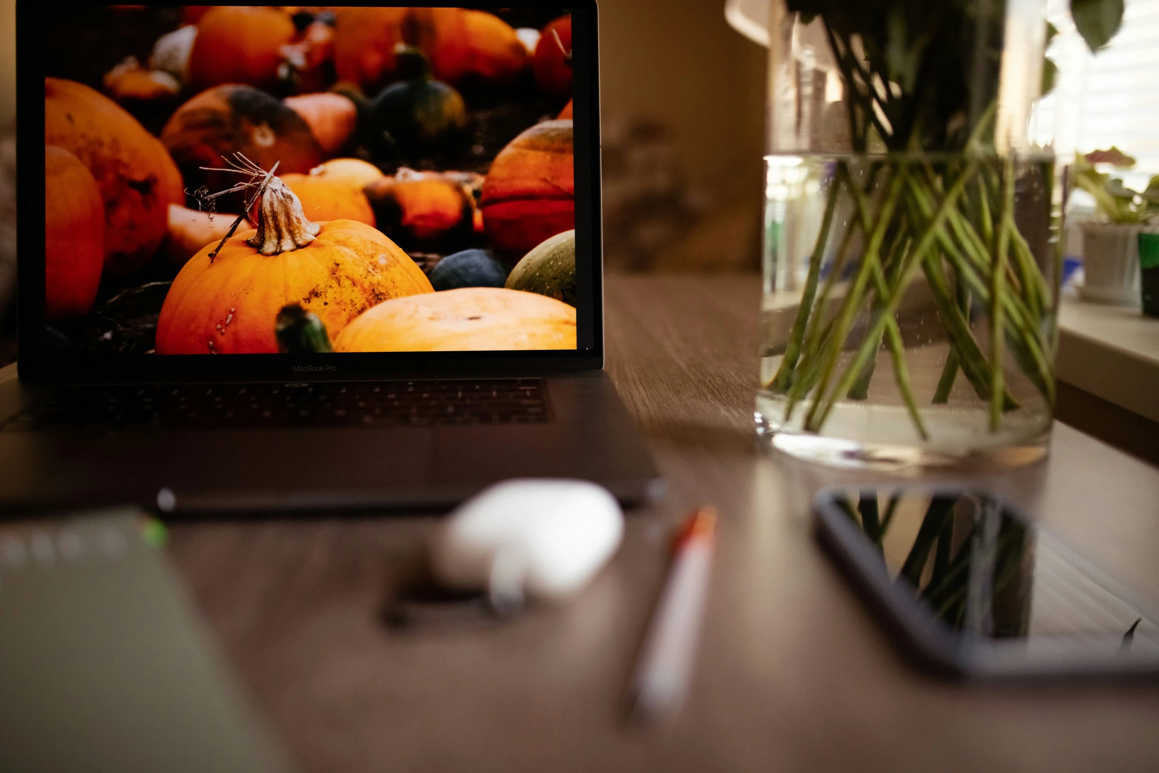 a vase with oranges in it sitting on a desk