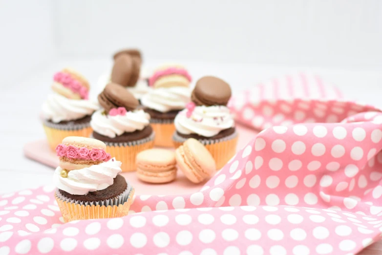 several small cupcakes with different frosting sitting on polka dot paper