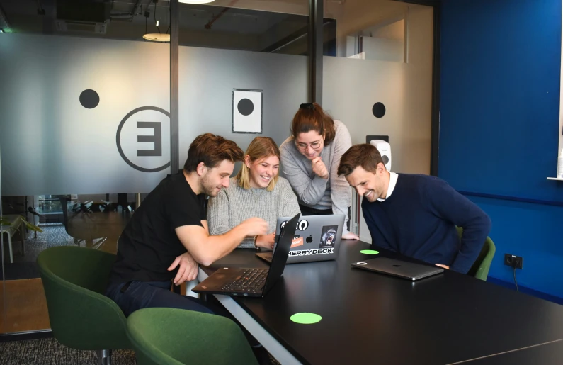 four people gathered around a laptop computer