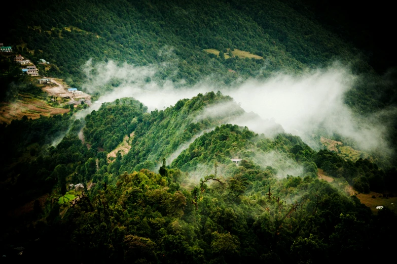 a view of a mountain range and some clouds over trees