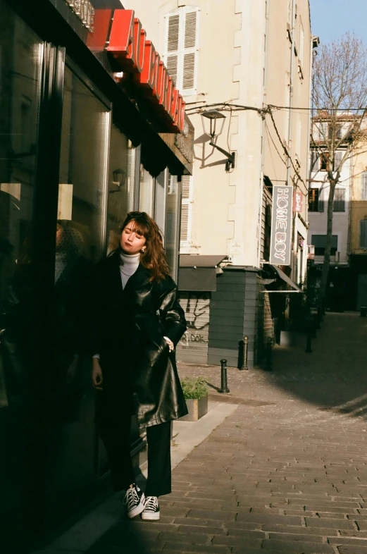 a woman standing next to the entrance of a building on a sidewalk