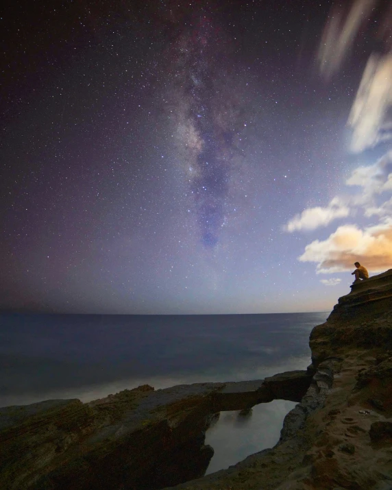 a man stands on a cliff against the background of a night sky