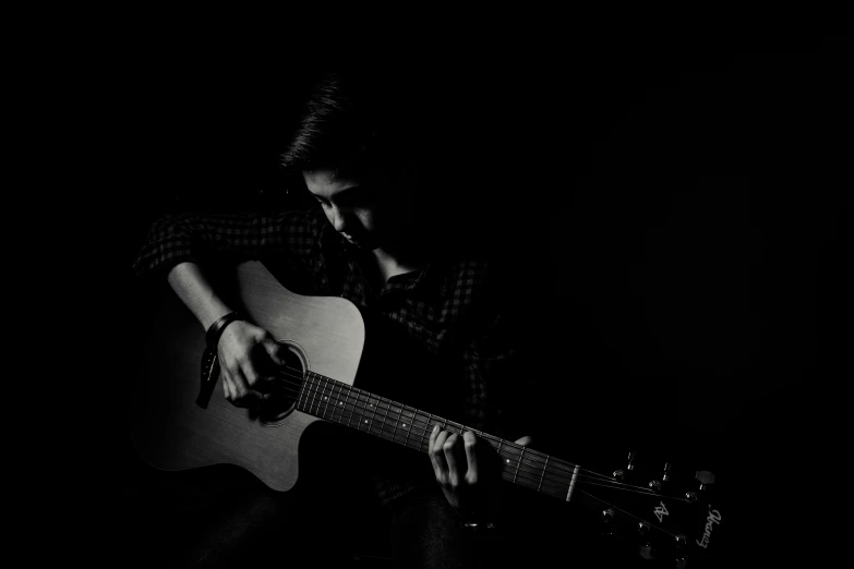 a black and white pograph of a man playing an acoustic guitar