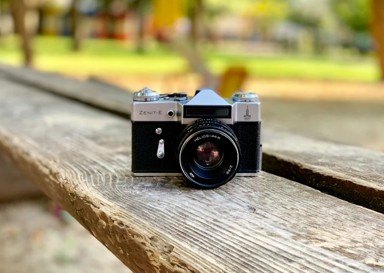 an old camera is sitting on top of the wooden bench