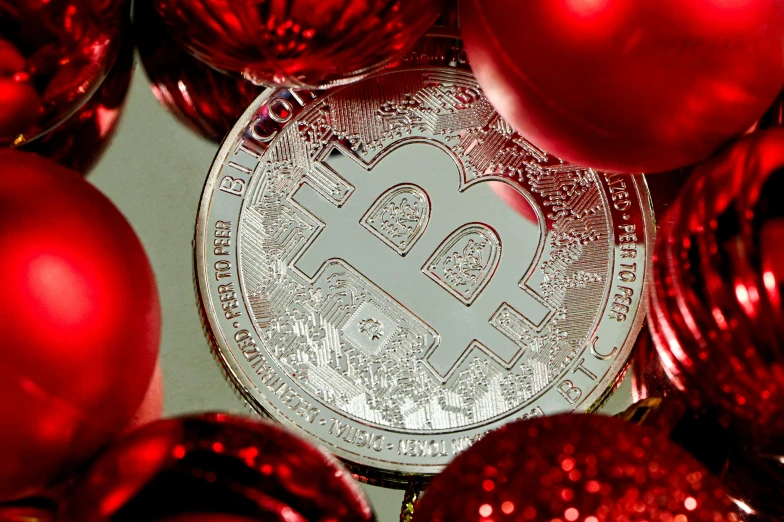 a bitcoin is surrounded by red ornaments and shiny balls