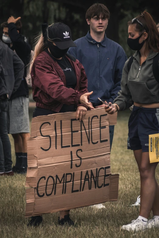 several people stand together in the grass holding a sign