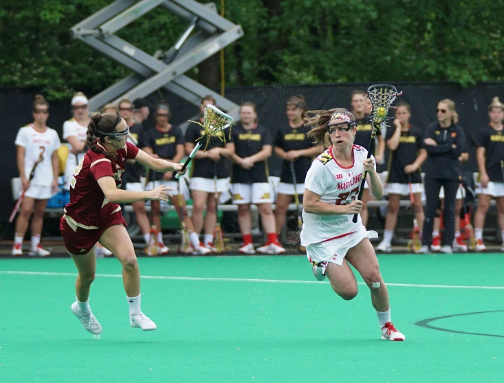 a girl playing field hockey gets ready to block another player