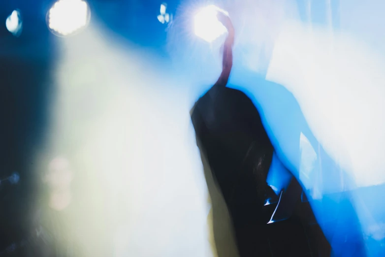 a man performing on a stage with spotlights behind him